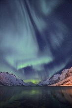 Aurora over a fjord with snow-covered mountains