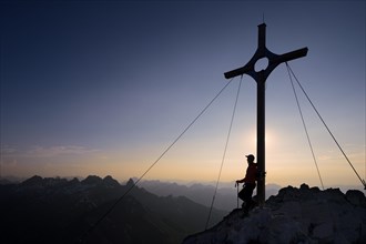 Mountaineer at the summit cross on Grosser Krottenkopf Mountain at dusk