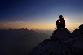 Mountaineer sitting on a rock on Grosser Krottenkopf Mountain at dusk
