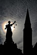 Justitia statue in front of the silhouette of the Old St. Nicholas Church
