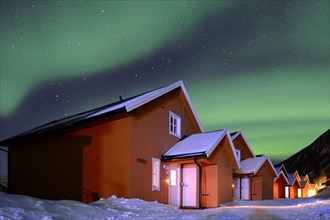 Red fishing huts in winter with Northern Lights
