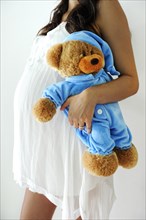 Woman with a pregnant belly holding a teddy bear