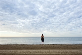 Woman wearing a black dress standing by the sea