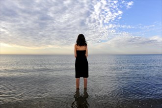 Woman wearing a black dress standing in the water of the sea