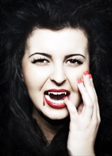 Young Woman dressed as a vampire with blood on her red lips