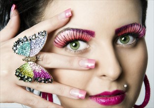 Young woman wearing artificial eyelashes and a butterfly as a ring