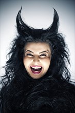 Laughing young woman dressed as a devil with horns
