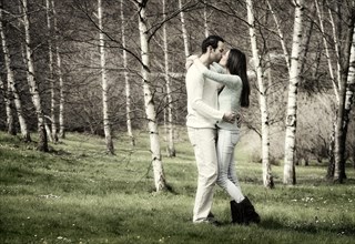 Young couple kissing in a birch forest