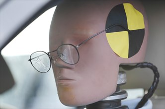 Crash test dummy in a car with slipped and broken glasses