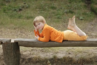 Little boy lying on a bench