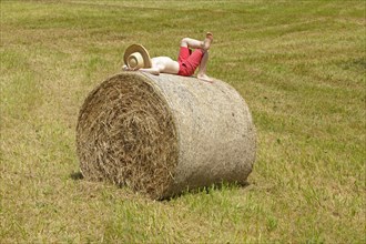 Boy lying on a bale of straw