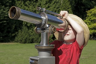 Young boy looking through a telescope