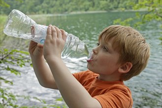 Boy drinks water from a plastic bottle