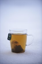 Tea cup with herbal tea standing in the snow