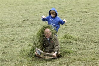 Boy throwing hay on a man