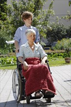 Grandson is pushing his grandmother in a wheelchair