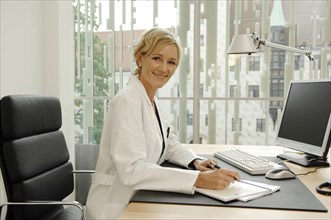 Female doctor in white coat sitting at her desk