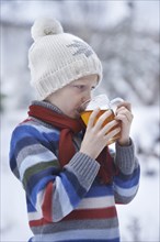 Boy in winter clothes drinking tea
