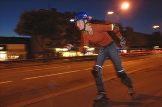 Woman on inline skates wearing a helmet and lights at night