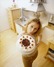 Woman in a kitchen holding a Black Forest cherry cake