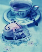 Half-eaten heart-shaped petit four and an old coffee cup