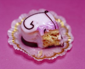 Half-eaten pink heart-shaped petit four