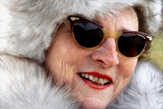 Old woman in a fur coat with a fur hat and sunglasses