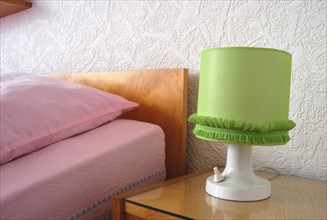 Green bedside lamp and a bed with pink sheets