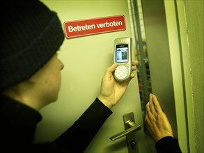 Burglar using a camera phone to take a photograph through the gap of a door