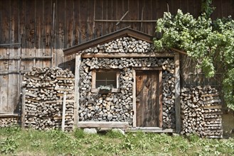 Stack of firewood in the shape of a log cabin with a rustic front door