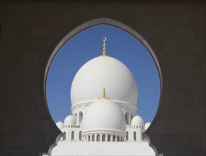 View of the domes of the Sheikh Zayed Mosque through an arched window