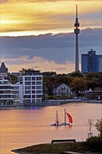 Two sailboats on Phoenix-See lake with Hoerder Burg Castle and Florian Tower at sunset