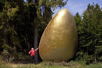 Man beside the sculpture 'What came first?' along the Waldskulpturenweg forest sculpture trail in Wittgenstein-Sauerland