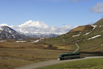 A shuttle bus crossing the Denali National Park and Preserve with views of Mt McKinley at back