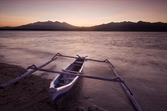 Fishing boat with outriggers at sunrise