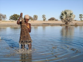 Ovambo girl fishing in a shallow pond