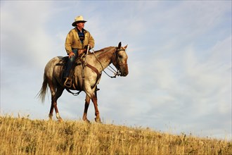 Cowboy riding a horse across the prairie