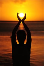 Woman holding the sun with both her hands