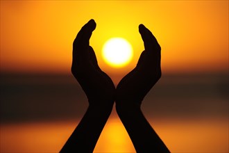 Two hands holding the setting sun
