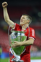 Bastian Schweinsteiger cheering jubilantly while holding the trophy