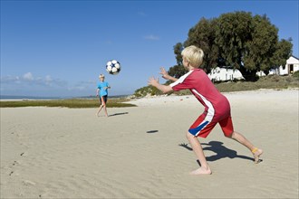 Boys playing football on the beach