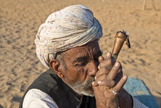 Indian man with a turban smoking a hash pipe