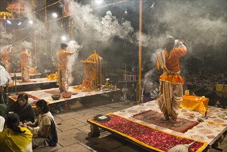 Four Brahmins swinging incense burners during a puja ceremony on platforms at the shore in honour of the Mother Goddess Ganga