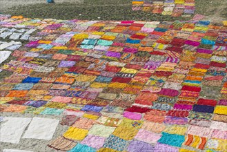 Colourful saris laying to dry after washing on a sandbank on the banks of the Yamuna River