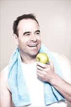 Man with a towel around her neck holding an apple