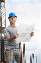 Construction worker wearing a hard hat and holding a building plan