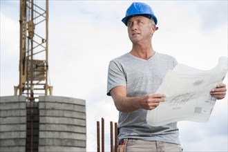 Construction worker wearing a hard hat and holding a building plan