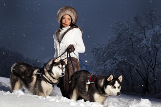 Young woman with huskies in the snow