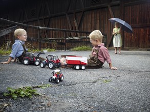 Children playing with toy tractors on farm