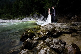 Bridal couple standing beside a torrent and looking lovingly at one another